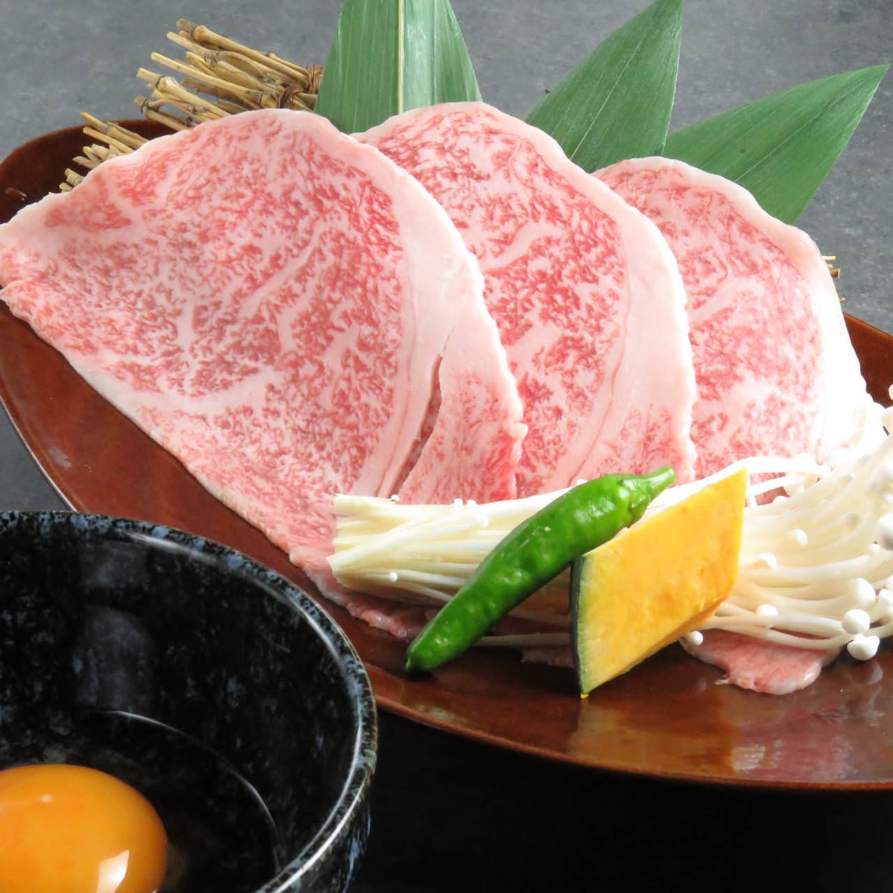 三枚の和牛が皿に並び、野菜や生玉子も添えられた「馬場ちゃん 新天地店」の広島名物コース
