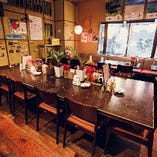 店舗中央に配された12人掛けのダイニングテーブル。皆でわいわいと食卓を囲む沖縄の文化を伝えています。小宴会からお一人様まで、様々なシーンにマッチするお席です。