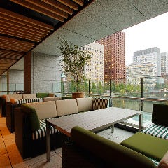 東京のオフィスビルと皇居を囲む水辺とグリーンを望むテラス席