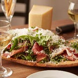 大きなプロシュットのサラダに、お客様の目の前でたっぷりとパルミジャーノを削る名物サラダ