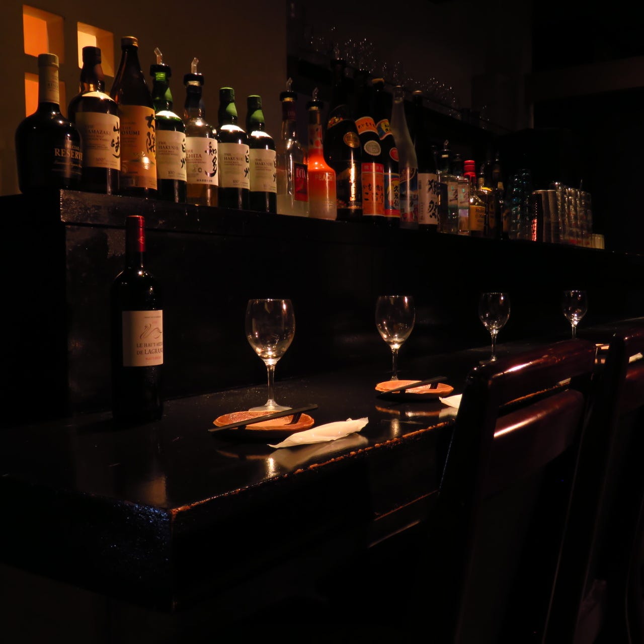 ワインが並ぶ間接照明のカウンター席