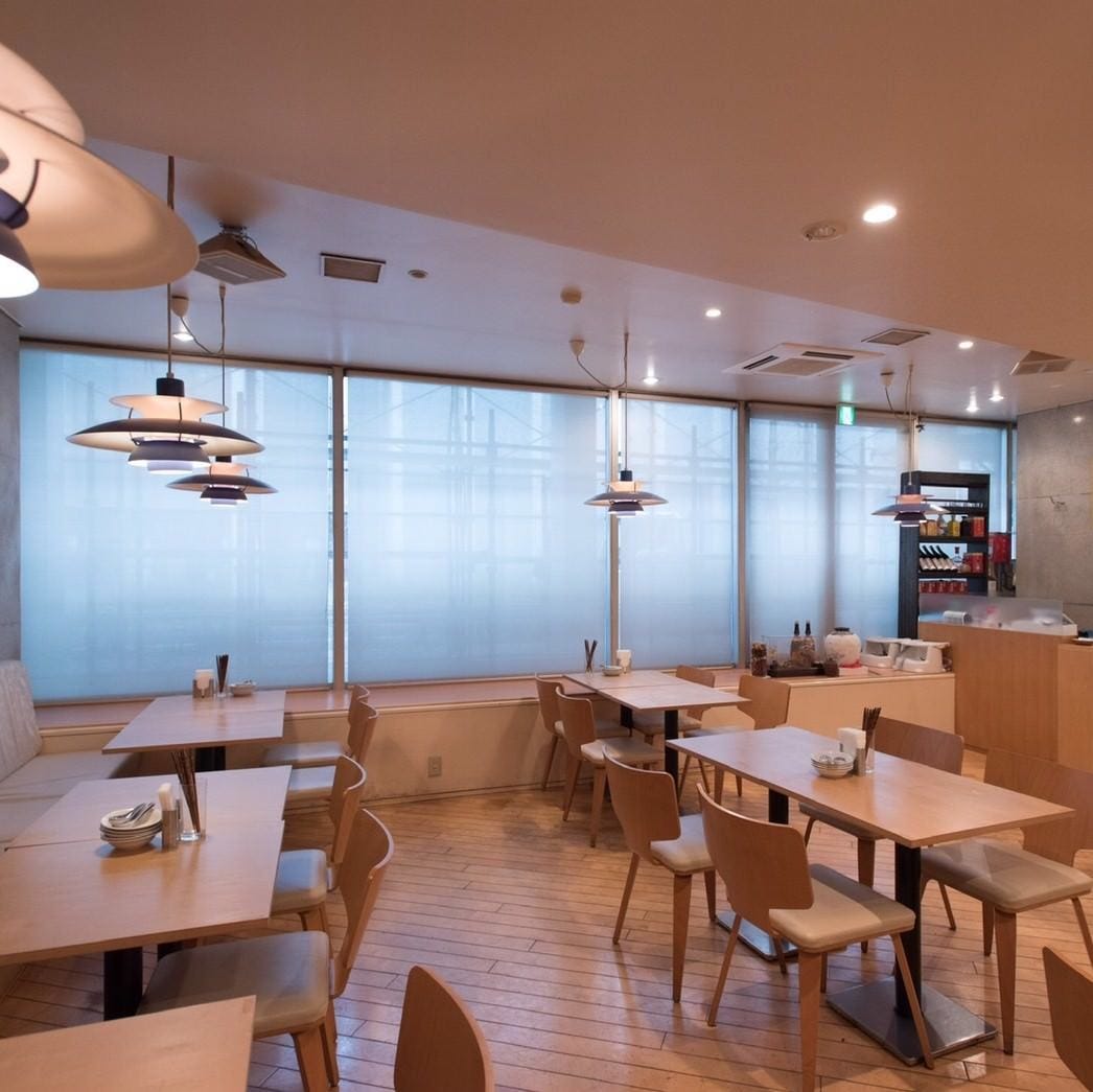 木製のナチュラルなテーブルと椅子がならんだ清潔感ある中華料理 信悦の店内