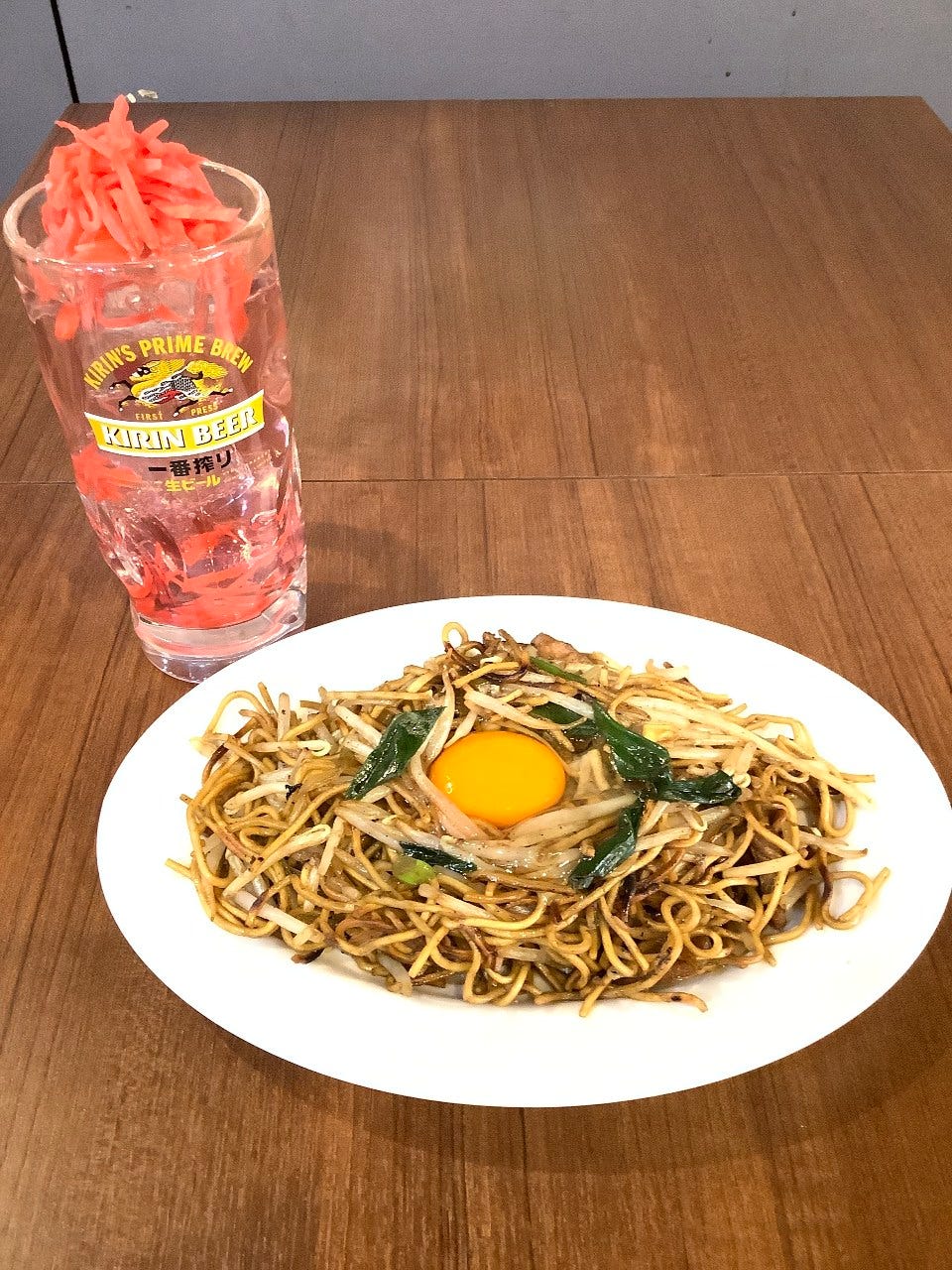 紅しょうがをたっぷりとのせたジョッキと、生たまごを添えた両面焼きそば