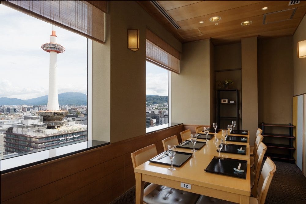 大きな窓から京都タワーを臨む黒いお盆が並んだテーブル席