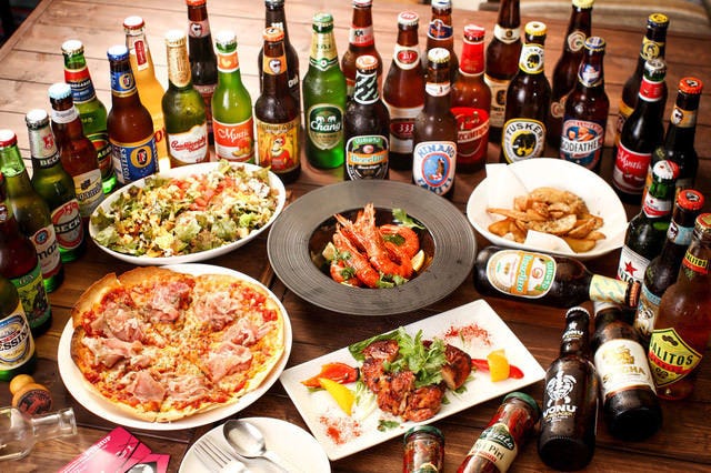 生ハムとモッツァレラチーズのトッマトソースピザや シーザーサラダなどウユニ塩湖の料理が並べられている様子