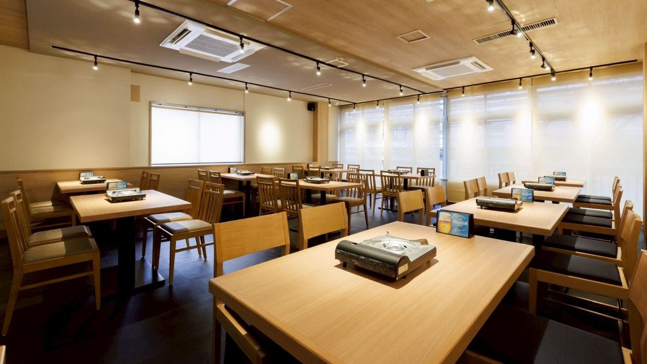木のテーブルが並んだ落ち着いた照明の店内