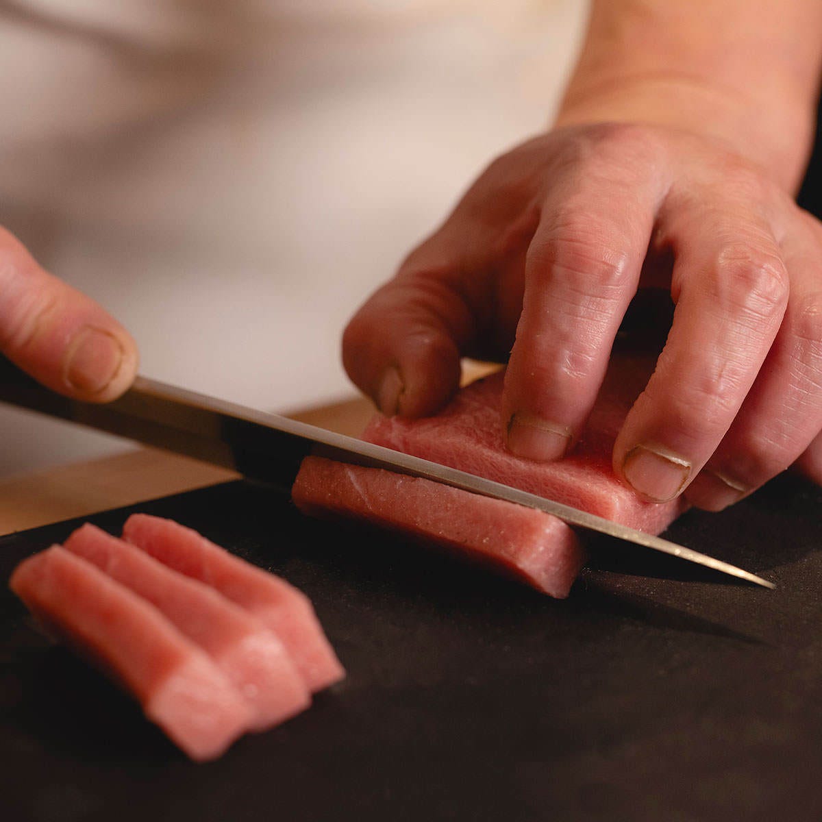 築地すし好 ヤエチカ店の赤身を包丁でカットしている様子