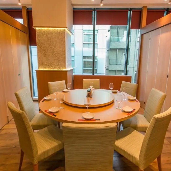 上野北京火考鴨店の個室。円卓と白いテーブル、窓沿いにソファー席