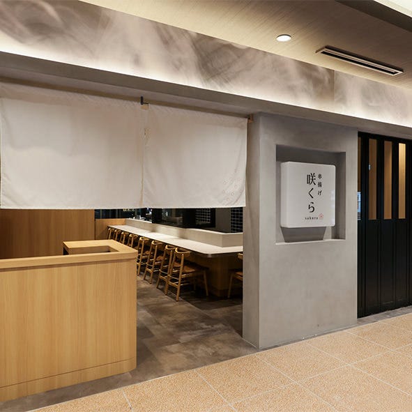 白い暖簾の奥にカウンター席が見える串揚げ咲くらKITTE大阪店外観