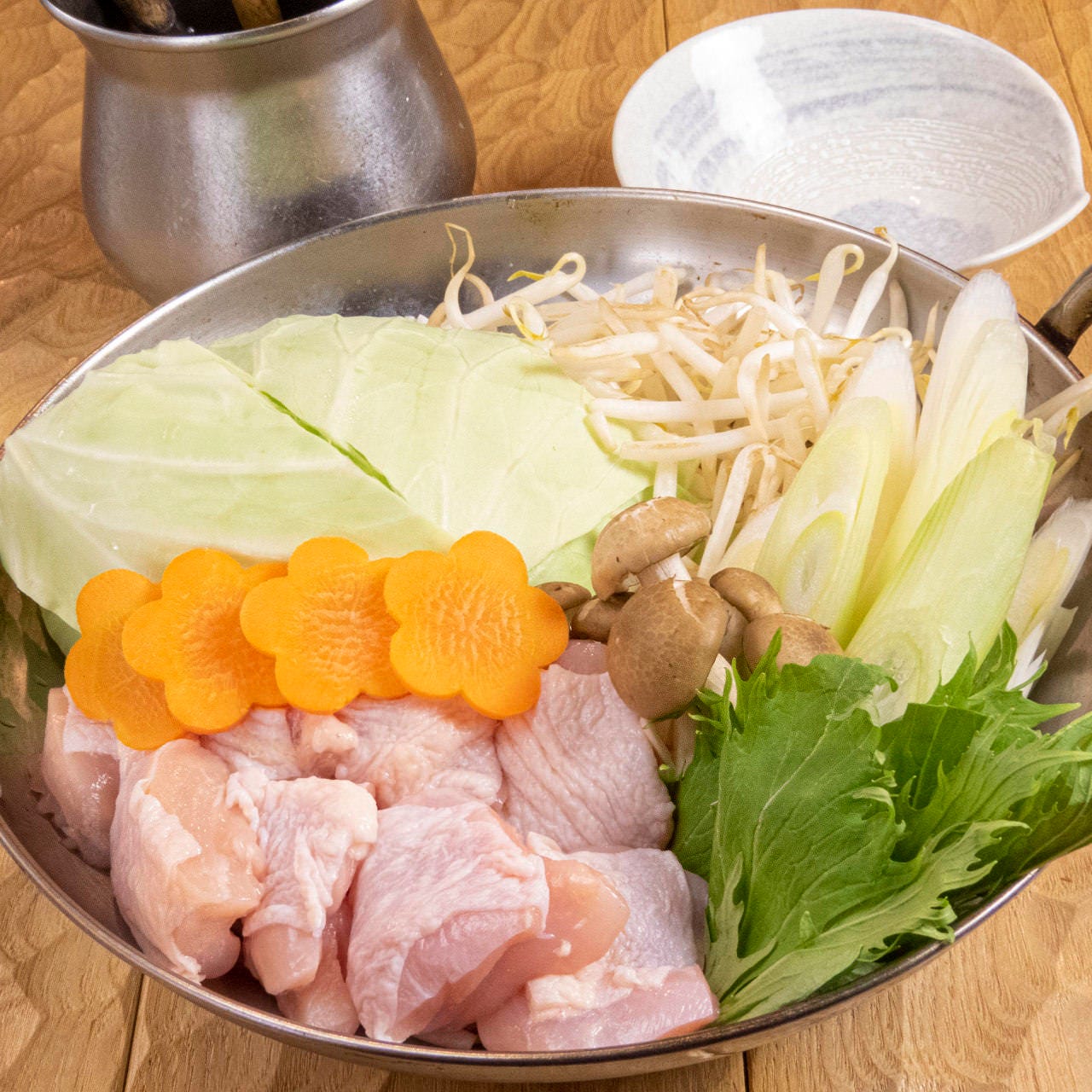 鶏肉や野菜がたっぷりと盛りつけられたば鍋料理が並んでいる様子