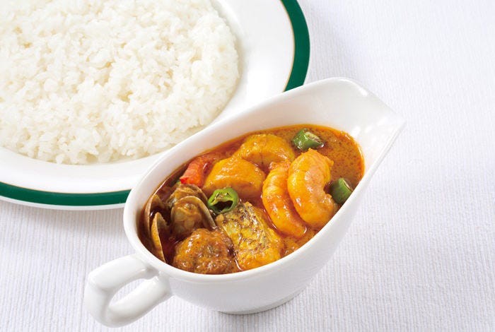 白いクロスが敷かれたテーブルにごはんが盛られた白いお皿とシーフードカレーが入ったグレイビーボートが置かれている