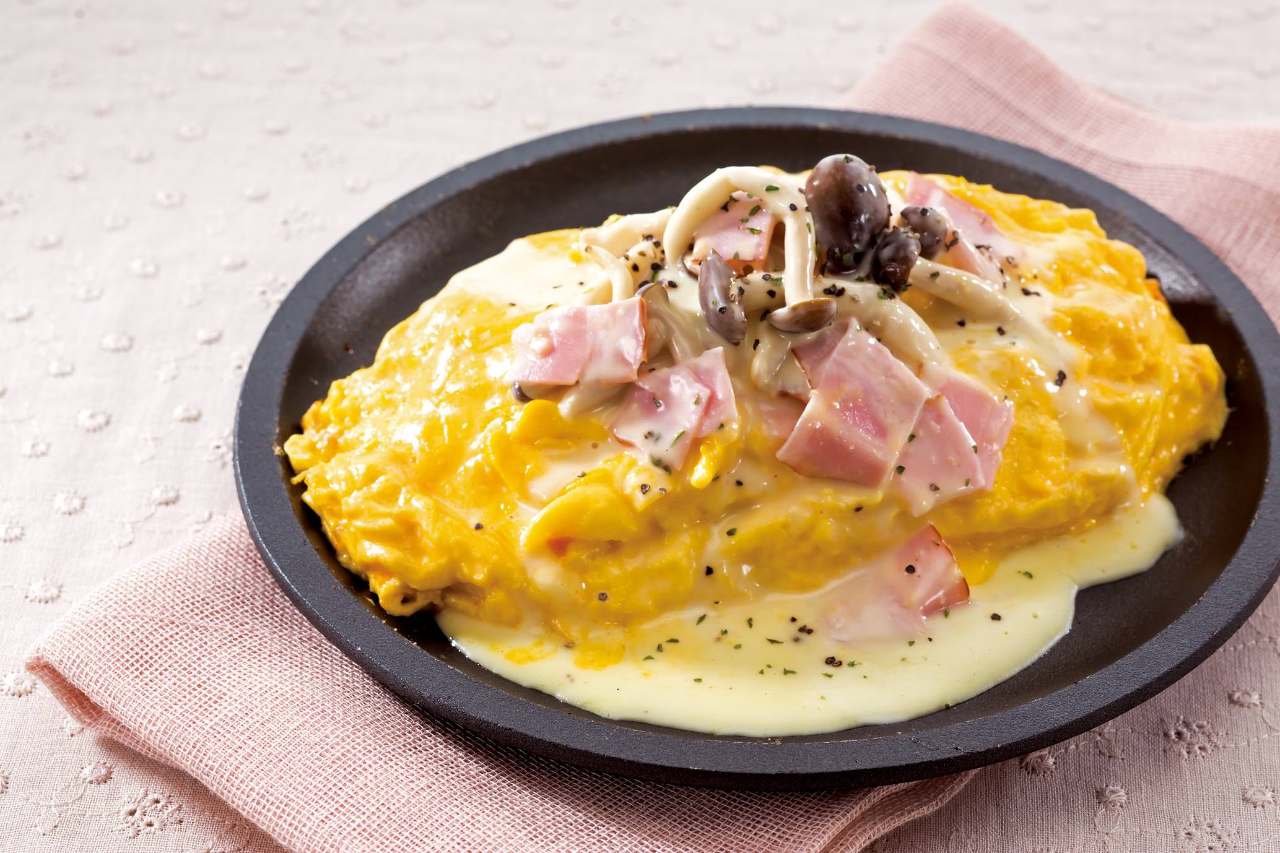 黒いお皿にクリームソースがかかったオムライスが盛り付けられている