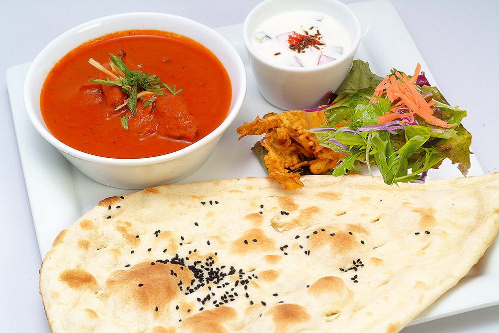 白い四角皿にナン・カレー・デザート・サラダが盛り付けられている