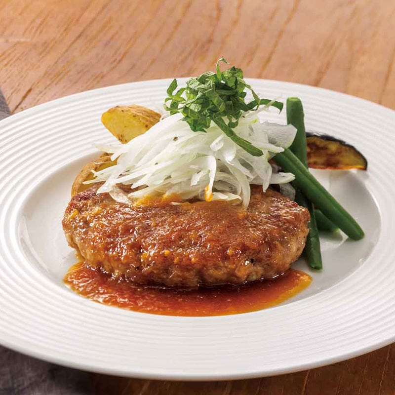 ネギや野菜がトッピングされてソースがかかったハンバーグ