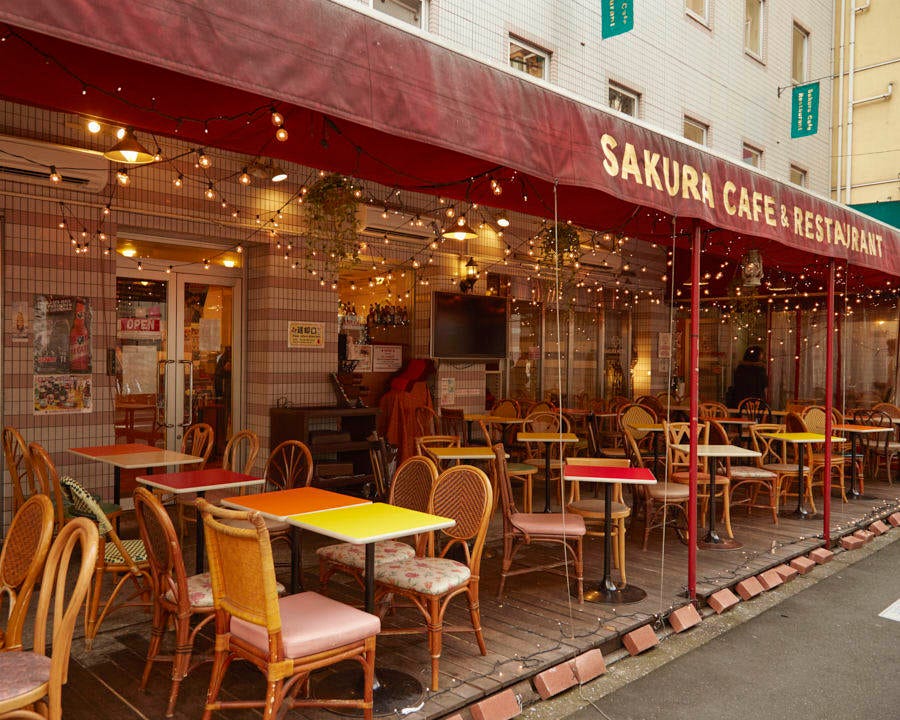 赤いテント屋根の下に並ぶ屋外テラス席のカフェ