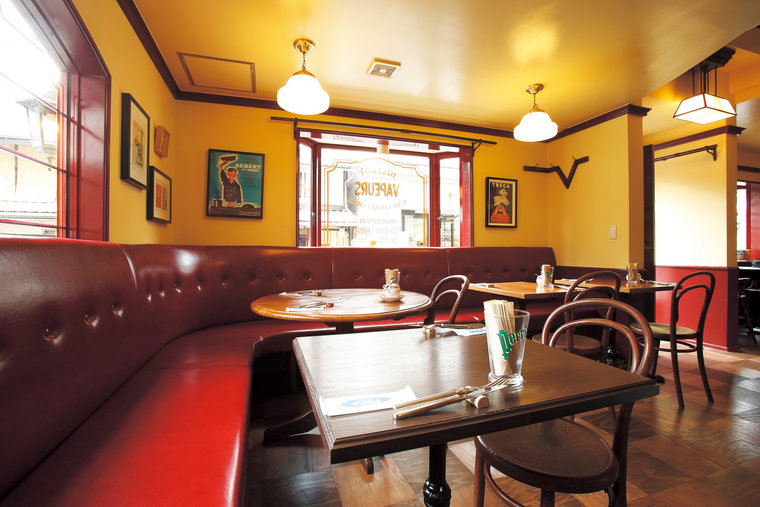 黄色い壁、赤いソファ席に木のテーブルが置かれたビストロ ヴァプール 烏丸御池の店内