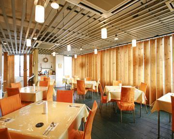 「食感パスタとピザのお店 ピノキオ」のオレンジ色のテーブル席が並んでいる