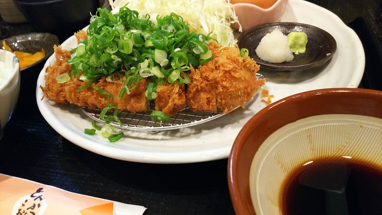 ねぎがのったとんかつに生卵やしょうゆダレが付く「とんかつこおち」の「揚げだしねぎとんかつ定食」