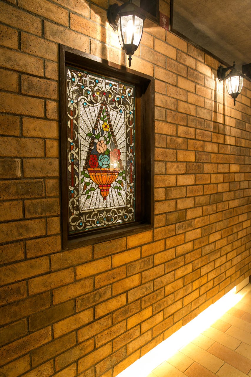 ステンドグラスが飾られた「神戸ホルモン 生田店 」のレンガ壁