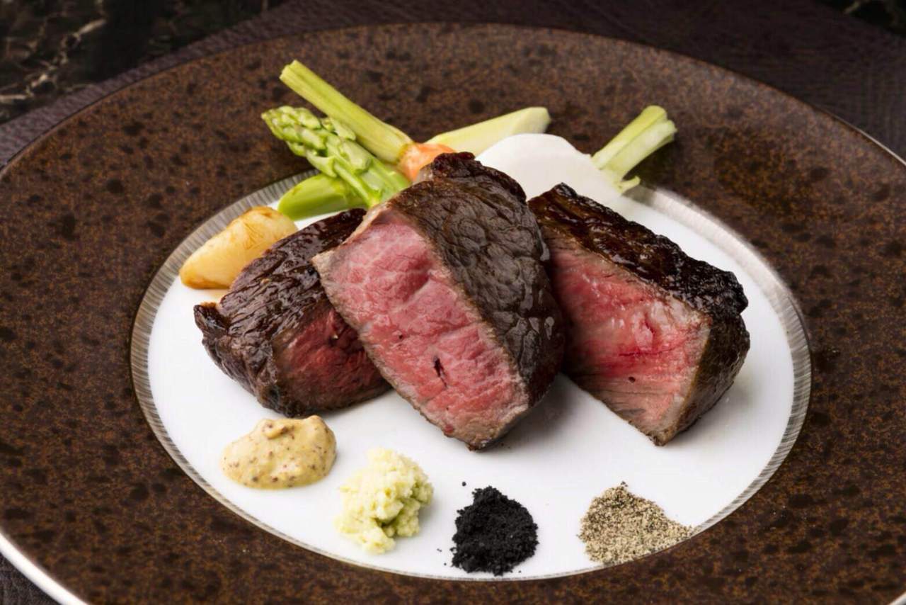 ブラウンと白のお皿に盛られたお昼のお肉コースのメインディッシュ