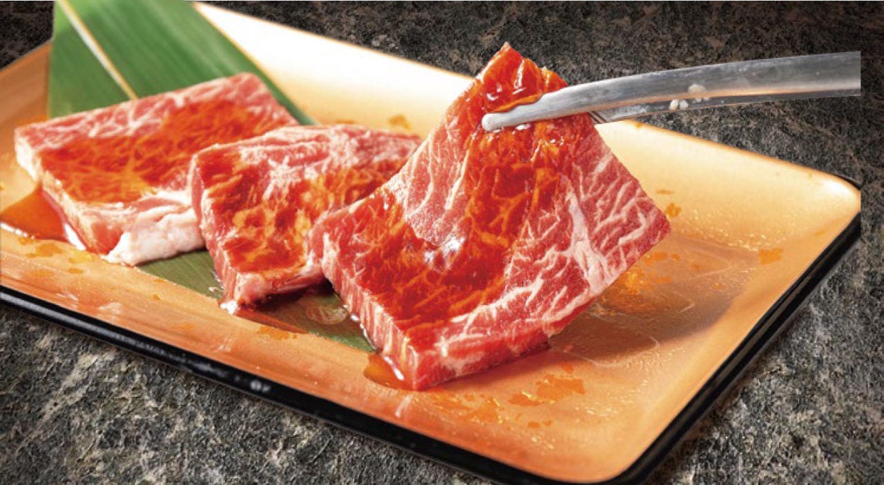 トングで焼肉じゅうじゅうカルビ 大和中央店の生肉を持っている様子