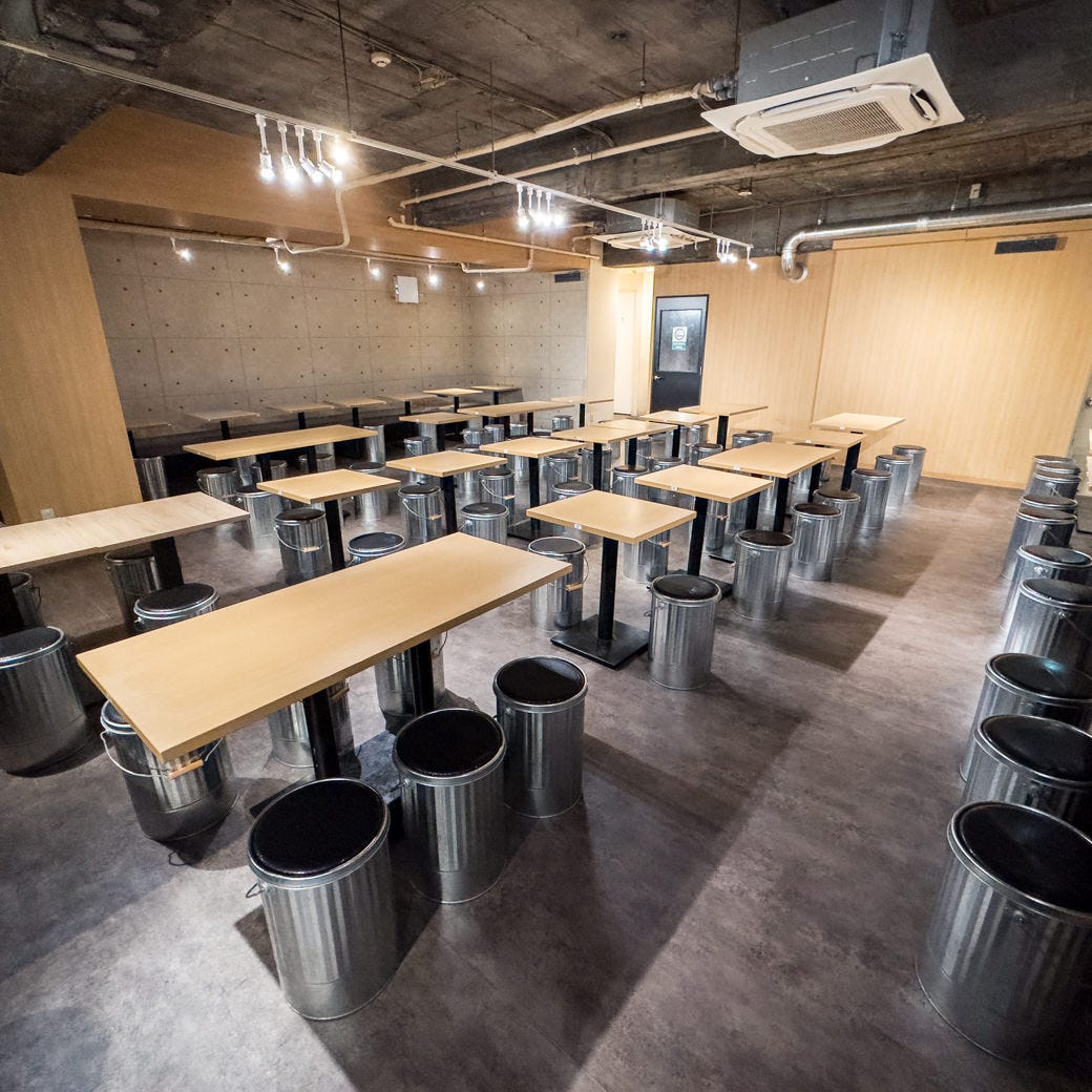 スケルトン天井やバケツ椅子などカジュアルな雰囲気のテーブル席が並んでいる居酒屋おすすめ屋 大宮店の店内