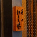 店前に掲げた木彫りの看板が目印。地下には同系列の魚料理専門店「吉成本店」がございます。