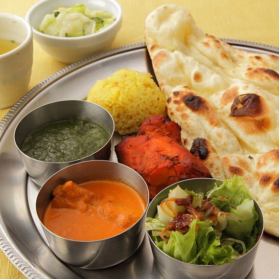 シルバーのお皿に盛られたナンやカレー、サラダ、タンドリーチキンなど
