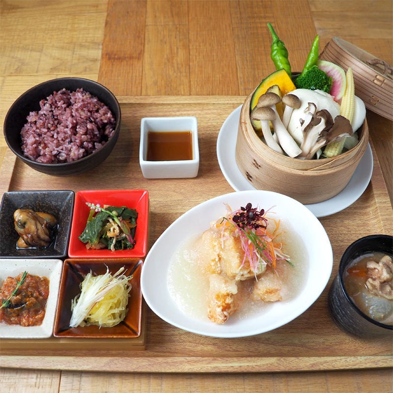 木のお盆に並んだ蒸し野菜と雑穀米、みぞれあんかけ、味噌汁、小鉢