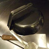 創業者・藤岡重次が生み出したキャップ。油のハネをふせぐためにフライパンをかぶせたことから生まれました。いまでは専用のものもありますが、写真はフライパンの柄を曲げて作っていた当時のキャップ。