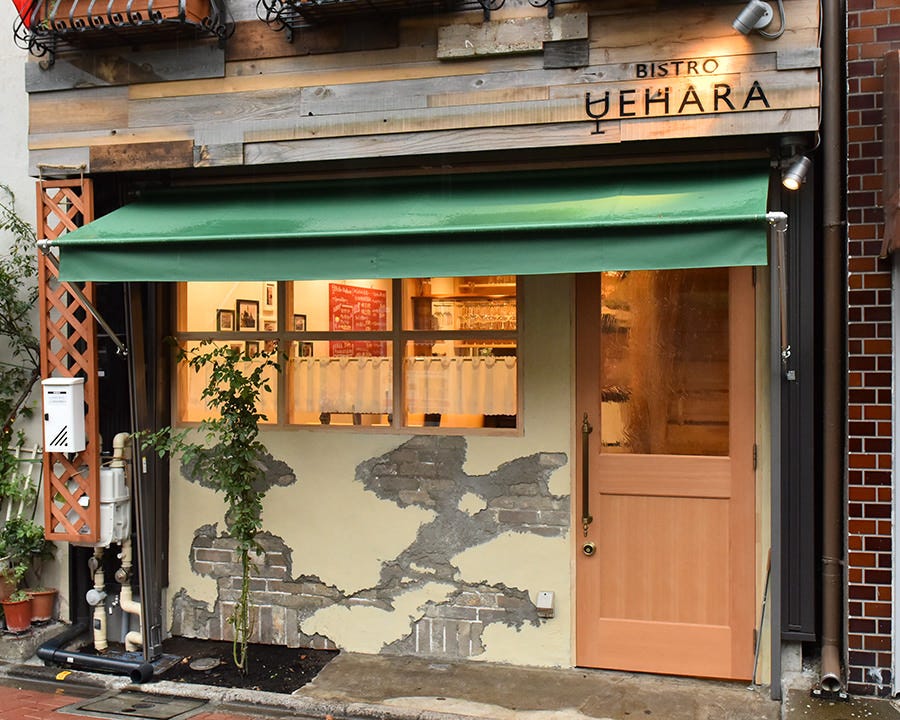 木製ドアがと緑の屋根が付いたビストロ ウエハラの外観