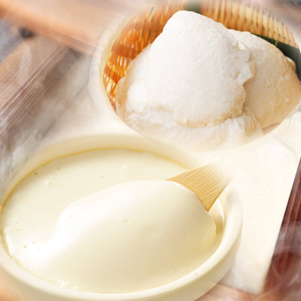 お椀に盛られたやわらかい豆腐と竹べらですくわれる豆腐