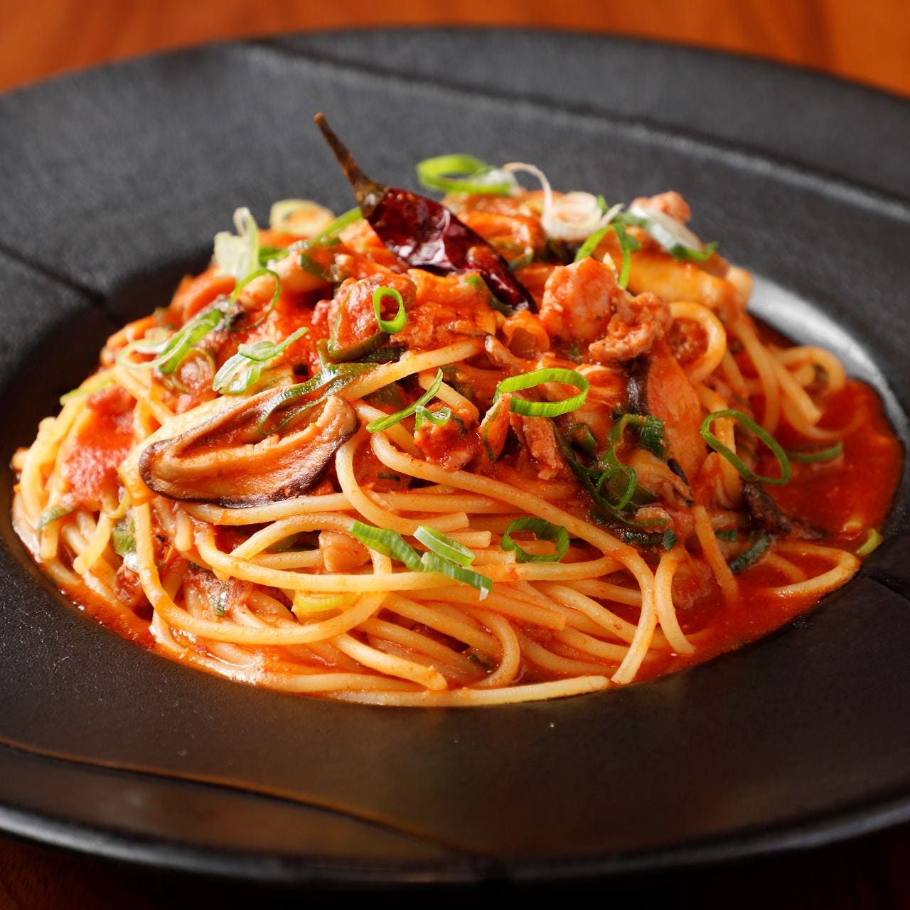 黒皿にパスタがのっている様子