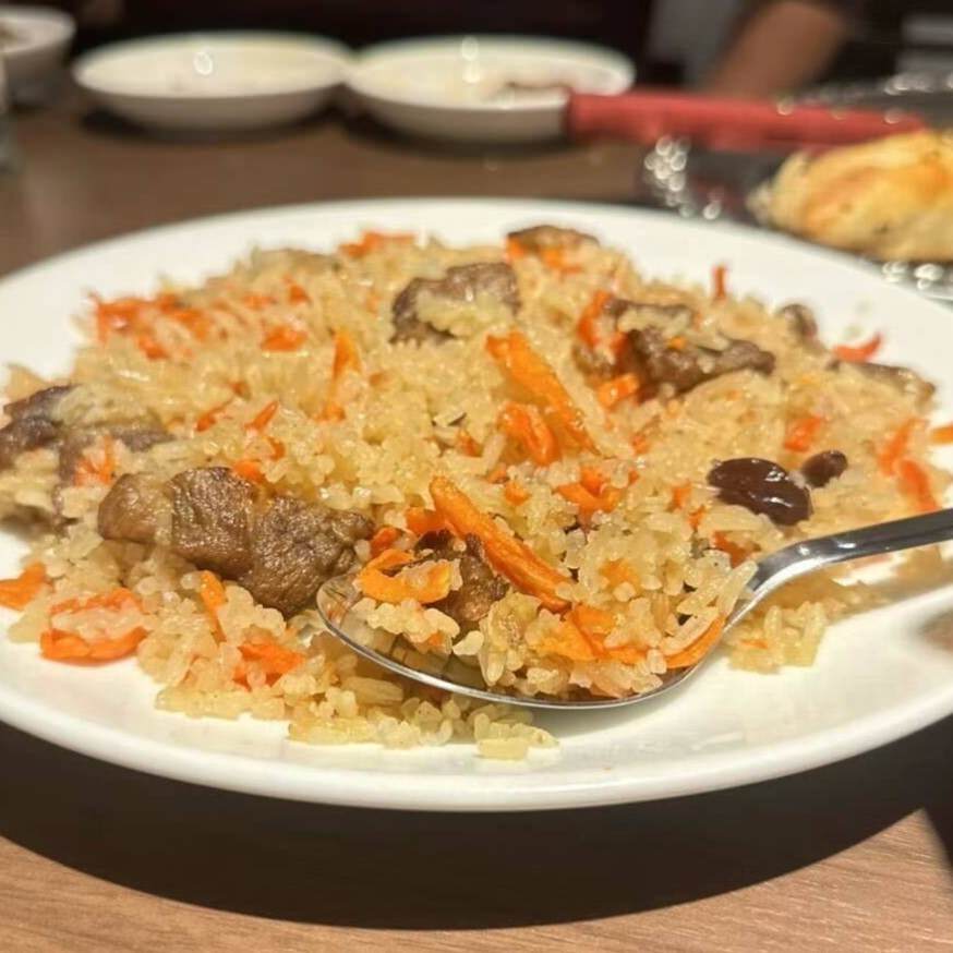 炊き込みごはんのようなポロをスプーンですくう様子