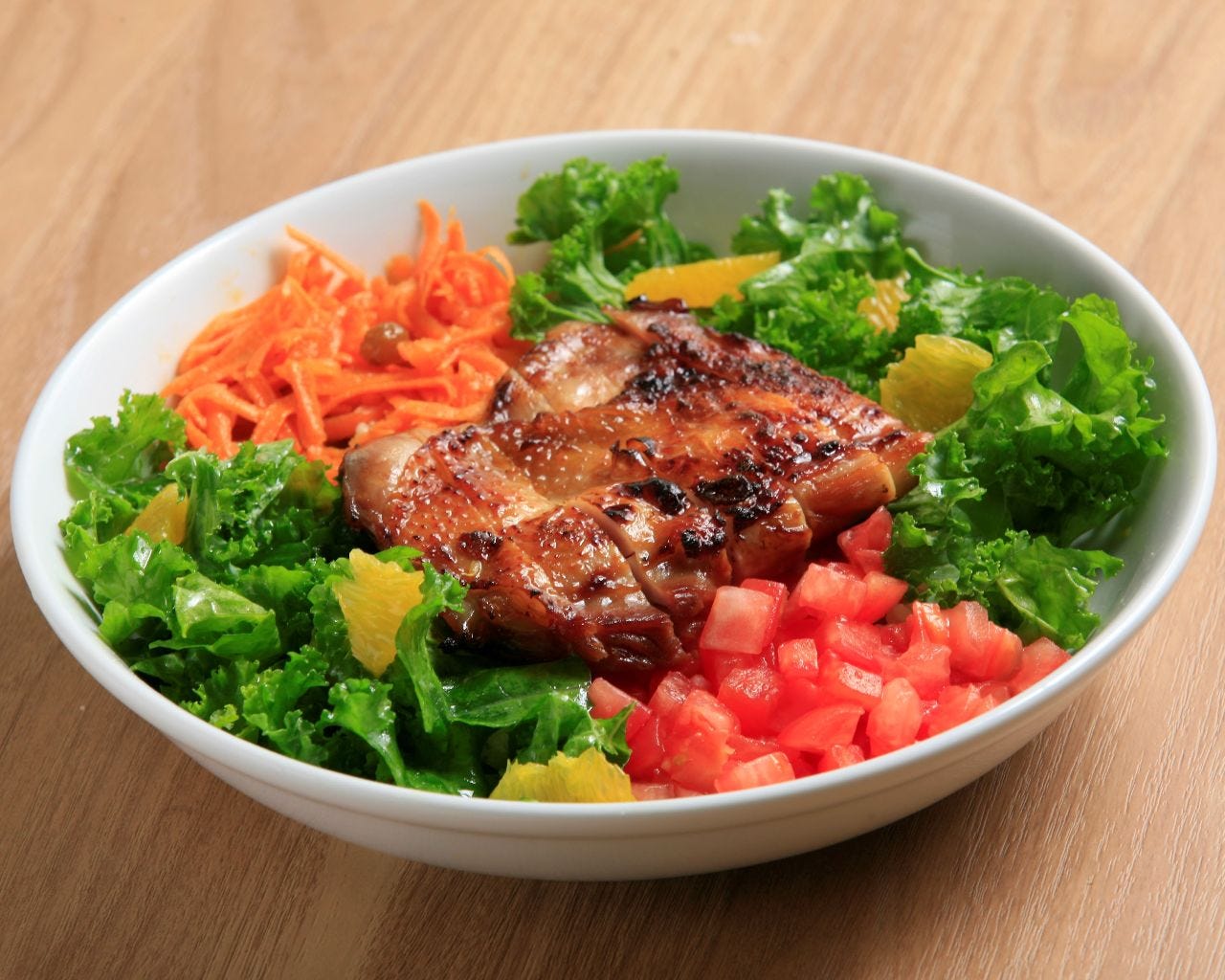 白い丸皿に盛り付けられたテリヤキチキンとケール トマトとキャロットラぺ ライスボール