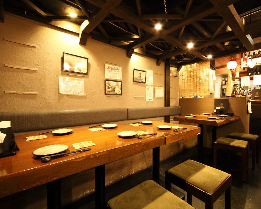 長いテーブルと椅子が並びオレンジ色の明かりがついている三代目 池袋じげもんとんの店内