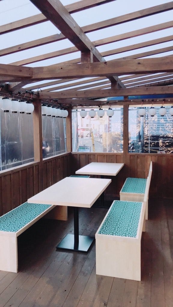 木の壁にシンプルな木製のテーブルといすが並ぶ、食堂のカジュアルな雰囲気