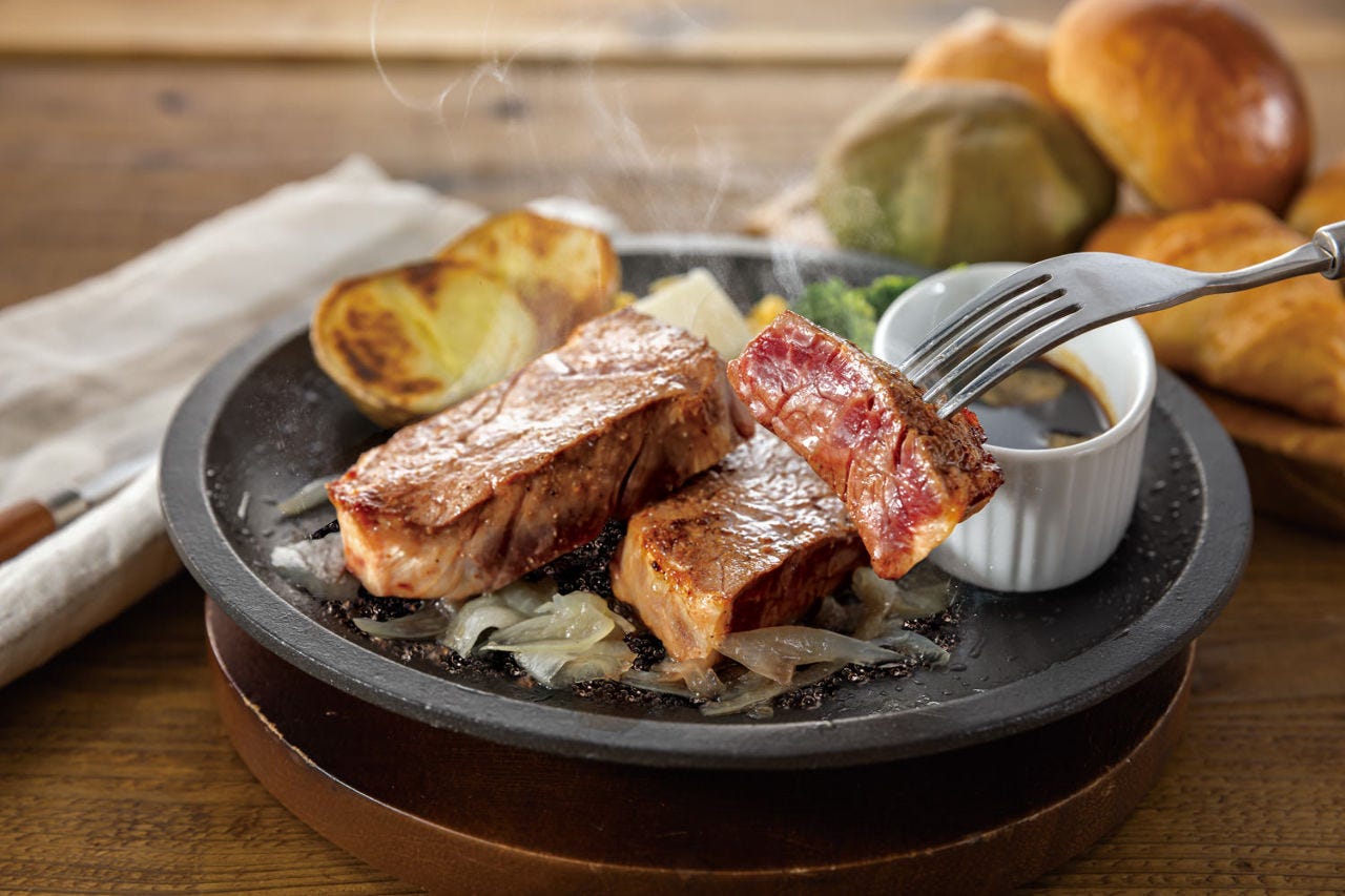 鉄板の上の厚めのステーキと肉を刺したフォーク