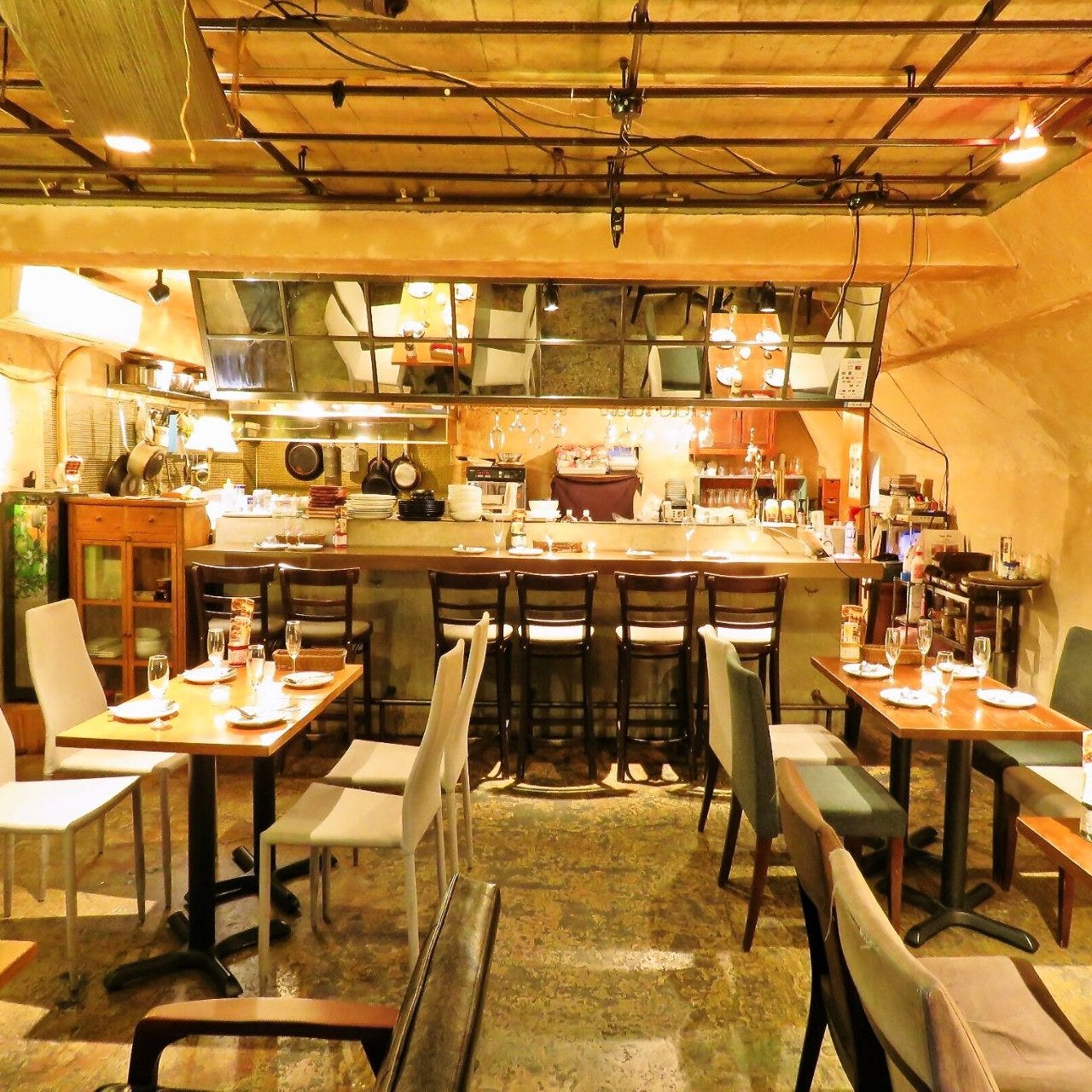 木のテーブルや白い椅子が並んだナチュラルな内観