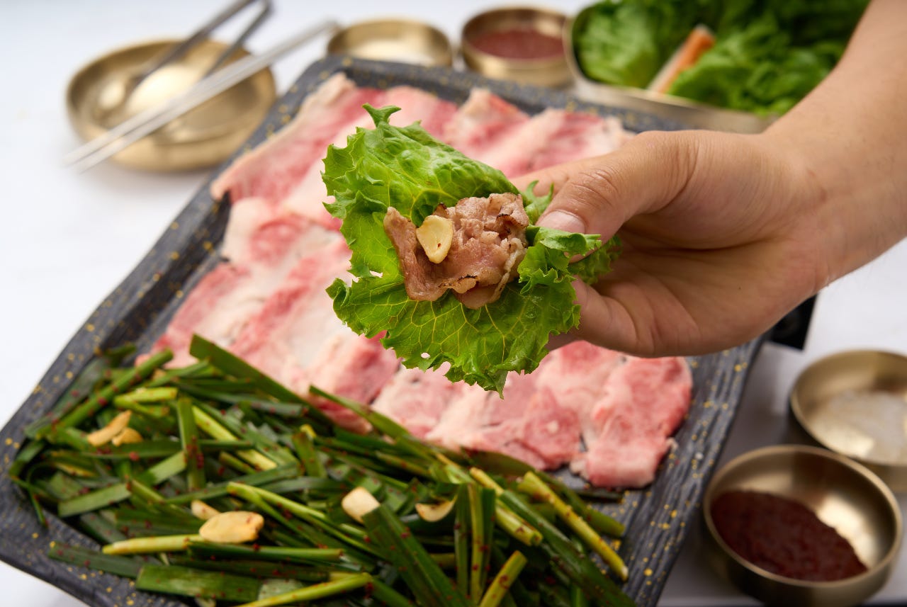 サムギョプサルの肉をサンチュで巻いている様子