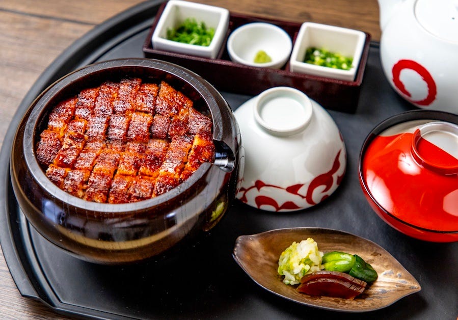 黒いお盆にのったひつまぶしと香の物、お吸い物、薬味