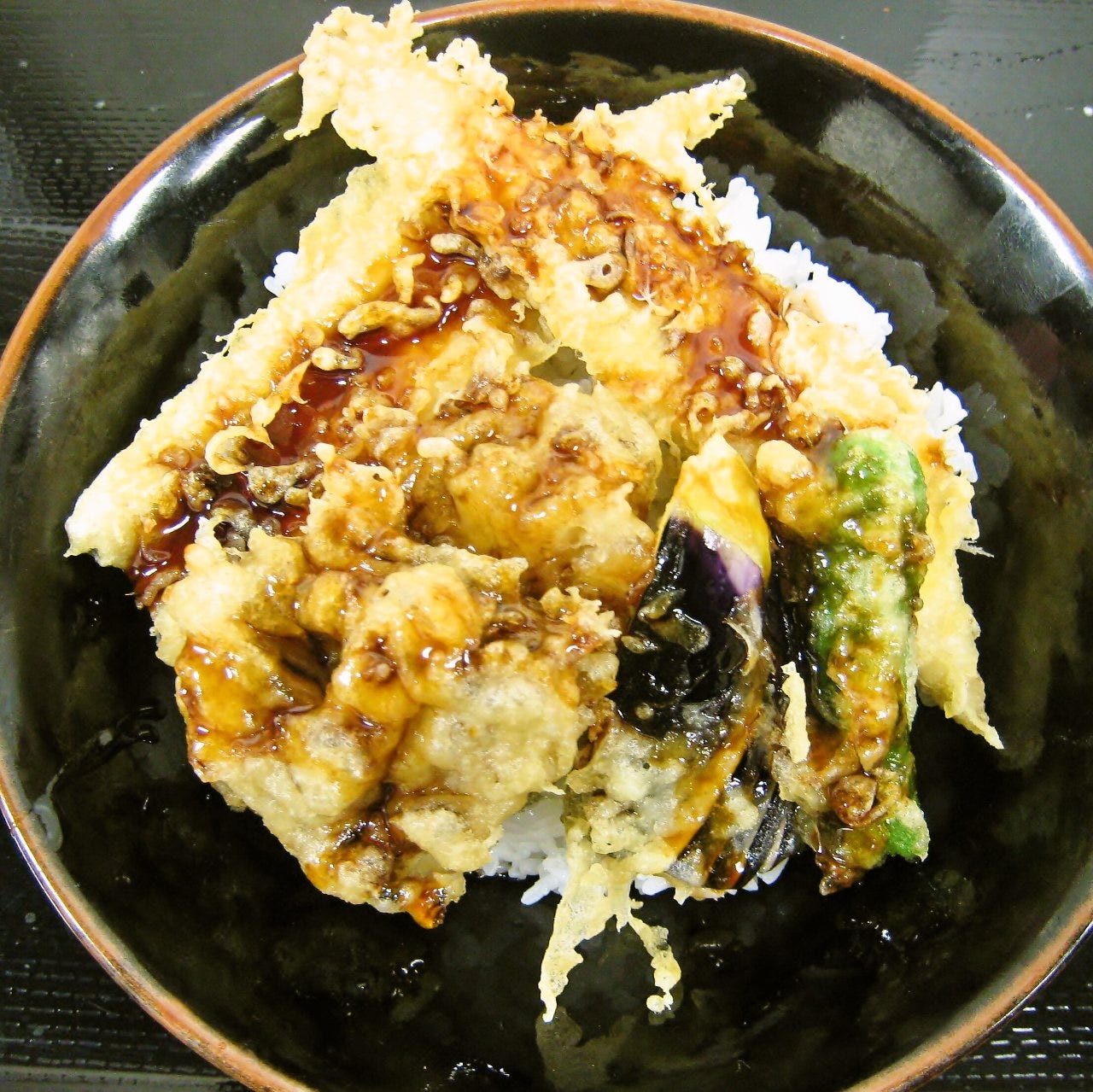 種類豊富な天ぷらの上に天つゆがかかっている特製天丼