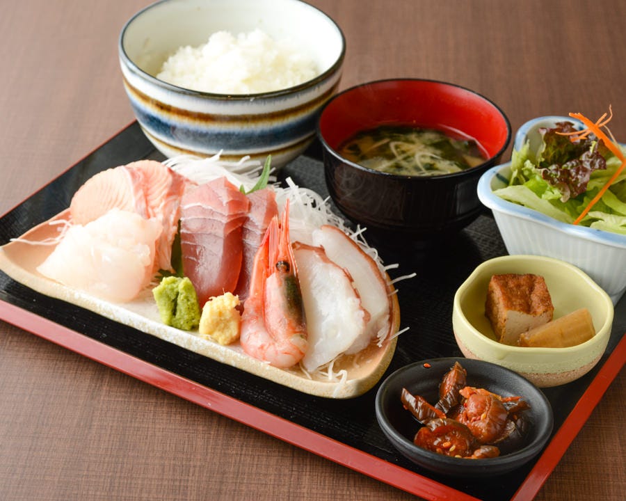 大きな切り身の刺身や小鉢、ごはんなどが並んでいる刺身定食のイメージ