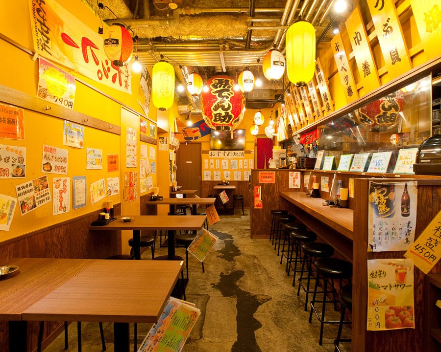 シンプルなテーブル席やカウンター席が並んだ居酒屋レイアウトのひだりうまでん助 立川 北口店の店内の様子