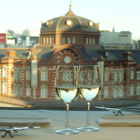 手前に白ワイン、奥に東京駅が見える「イゾラ スメラルダ 丸ビル」の内観