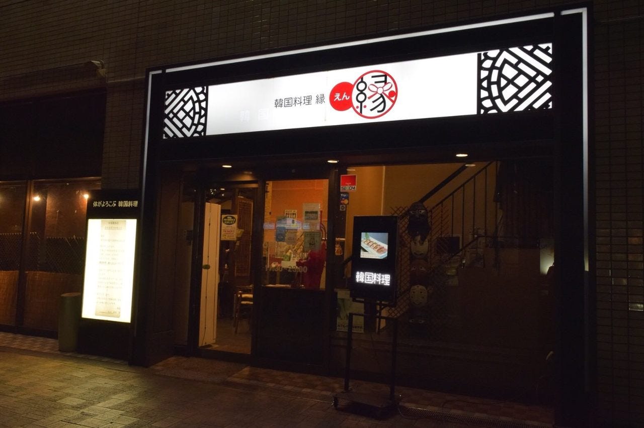 白く光るファザード看板が目立つ縁 さいたま店の夜の外観