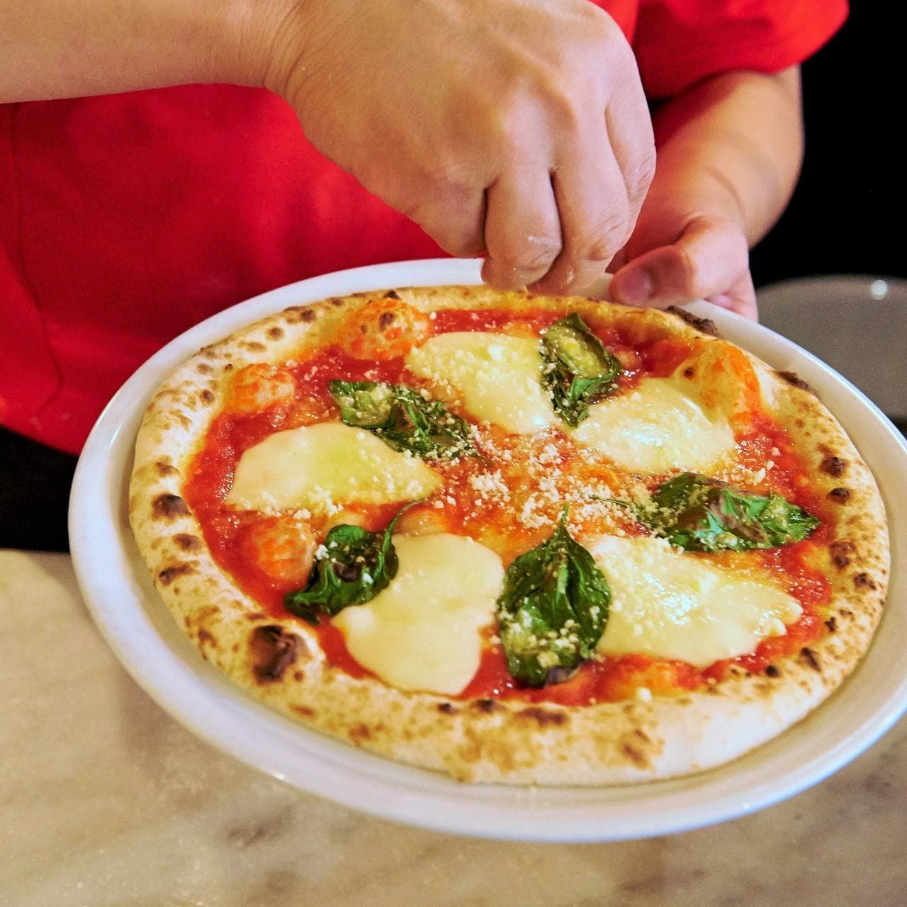 マルゲリータピッツァにチーズをかけている様子