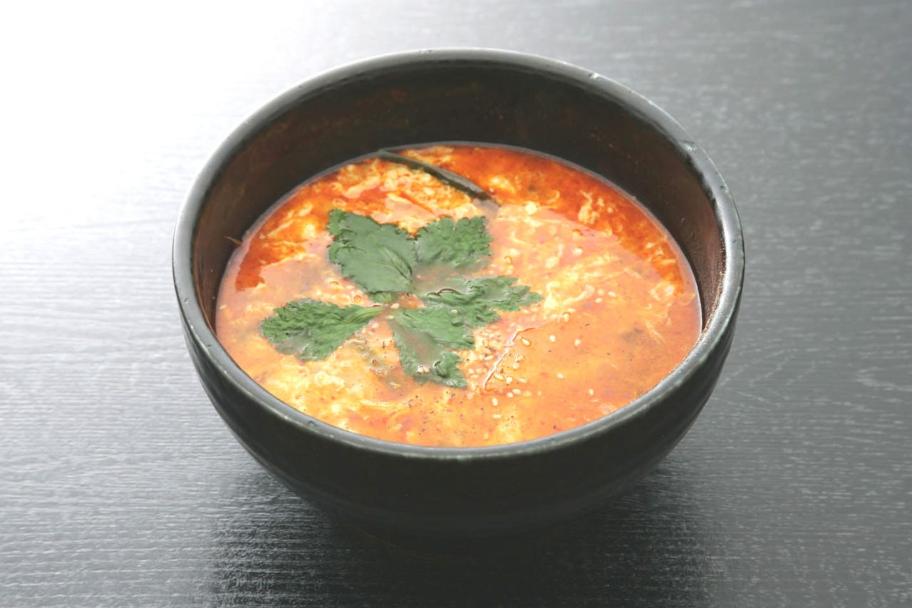 赤いスープにごはん、卵、葉野菜が入っているクッパ