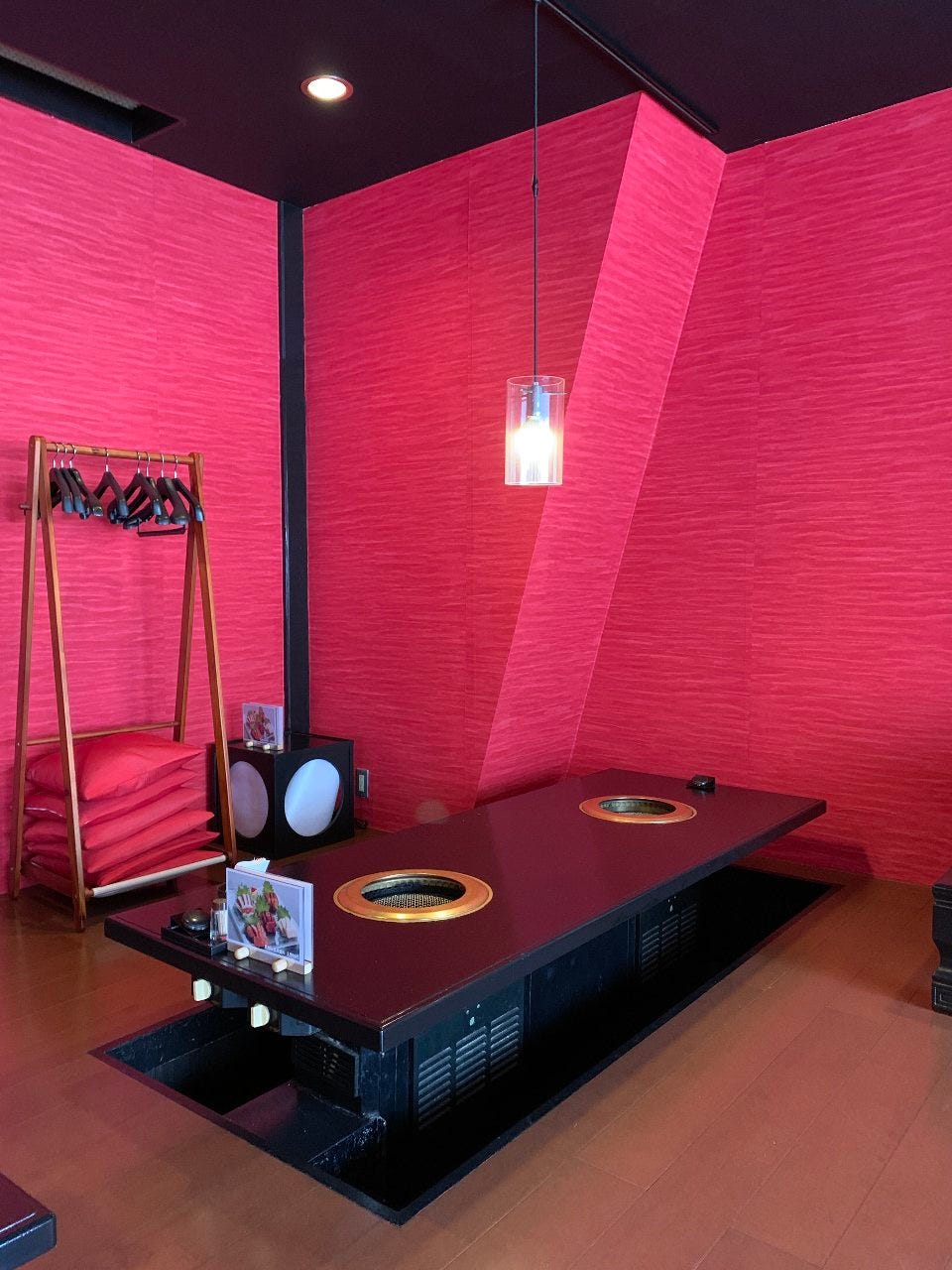 ワインレッドの壁に黒いテーブル、掘りごたつの座敷席