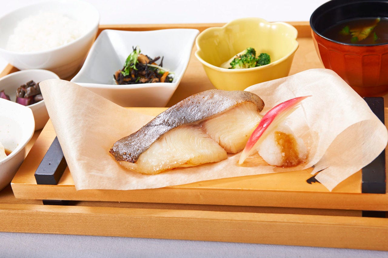 木のお盆にのった銀鱈の西京焼きと小鉢と味噌汁とご飯